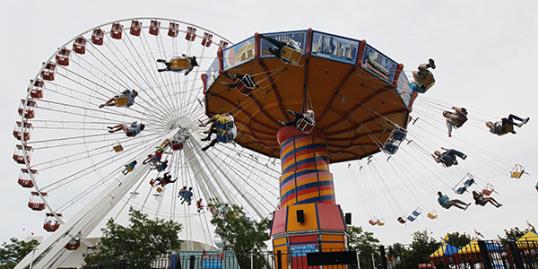 Photo: In this file photo photo, visitors ride on the Ferris Wheel and Wave Swinger at Chicago's nearly century-old Navy Pier. (AP Photo/Charles Rex Arbogast, File)