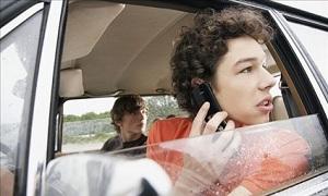 Distracted teen talks on cellphone while driving (© Corbis)