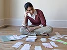 Image: Woman looking at bills and receipts on floor (© David Sacks/Lifesize/Getty Images)