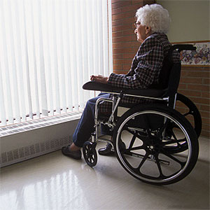 Senior woman on wheelchair looking out of window with blinds © Design Pics, Don Hammond, Design Pics, Getty Images