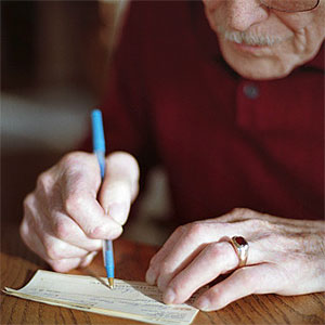 Senior man writing check © Dennis Wise, Photodisc, Getty Images