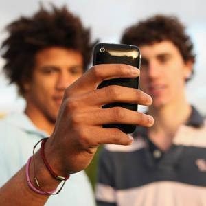 Boys using a smartphone to take a photo (© Juliet White/Digital Vision/Getty Images)