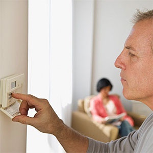 Man adjusting room temperature © Tetra Images, Tetra images, Getty Images