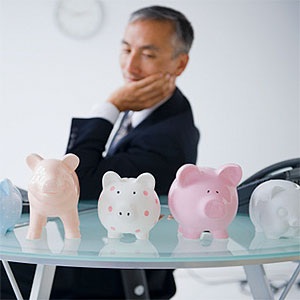 USA, Mid-Atlantic USA, New Jersey, Businessman looking at piggybanks standing on desk © Jamie Grill, Tetra images, Getty Images