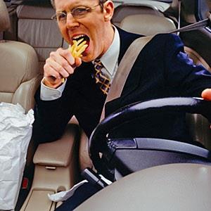 Image: Businessman devouring fries whilst driving car © Ryan McVay, Photodisc, Getty Images