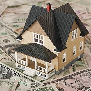 Toy house sitting on money © Vstock, Tetra Images, Corbis