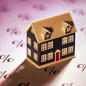Miniature home on sheet of percent signs © Comstock, Getty Images