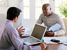 Image: Man sitting at dining table with financial advisor (Â© Corbis)