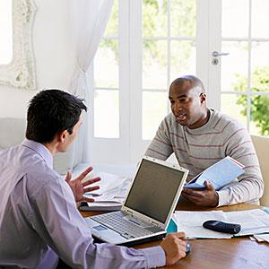 Image: Man sitting at dining table with financial adviser --Corbis