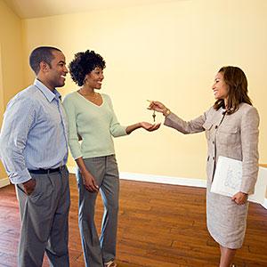 Real estate agent giving keys to couple in new home, copyright Mark Scott, Photodisc, Getty Images