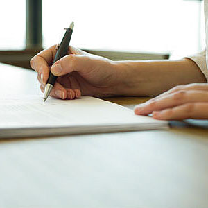Person signing insurance document copyright Eric Audras, PhotoAlto, Alamy
