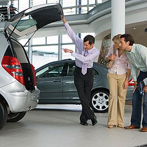 Car salesman showing couple new silver hatchback in car showroom copyright Juice Images, Cultura, Getty Images