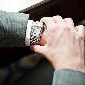 Man in suit checking watch Daniel Sheehan Photographers Digital Vision Getty Images