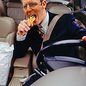 Businessman devouring fries whilst driving car copyright Ryan McVay, Photodisc, Getty Images