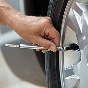  Man checking car tire pressure copyright Tetra Images, Tetra images, Getty Images