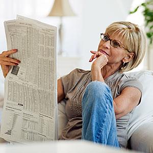 Woman reading newspaper in livingroom © Tetra images/Getty Images