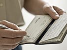 Image: A man holding a check book (© Image Source/Getty Images)