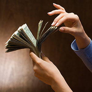 Logo: Woman counting money (Jose Luis Pelaez, Inc/Blend Images/Getty Images)