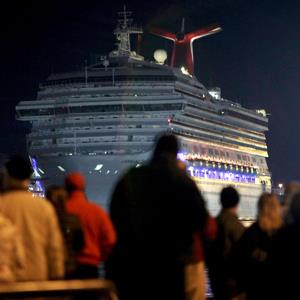 The Carnival Triumph cruise ship is towed towards the dock as spectators watch at the port of Mobile, Alabama on February 14, 2013 ( Lyle Ratliff/Newscom/Reuters)