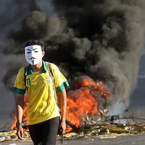 A masked protester walks away from a burning barricade near the Castelao stadium in Fortaleza, Brazil, on June 19, 2013 (© Andre Penner/AP)
