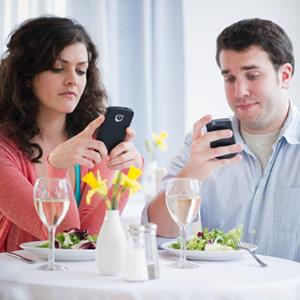 Couple using smartphones while in a restaurant (copyright Jamie Grill/Getty Images)