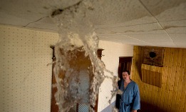 Man watching water stream from leak in ceiling (© Joel Sartore/National Geographic/Getty Images)