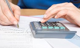 Man writing check, calculator, bills (© Dana Hoff/Getty Images)
