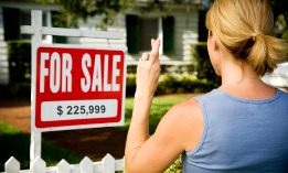 Woman in front of sale sign with fingers crossed (© SuperStock)