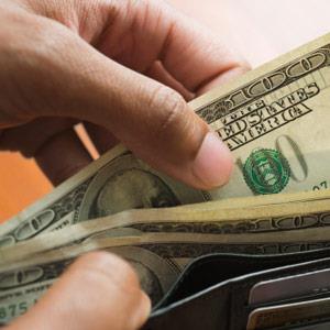 Man taking money out of wallet © Jose Luis Pelaez Inc/Blend Images/Getty Images