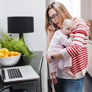 Mother talking on phone & holding baby (© Frank van Delft/Getty Images)