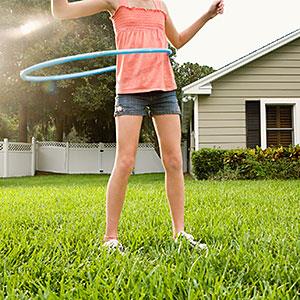 Girl hula hooping in backyard © Pauline St. Denis, Tetra images, Getty Images