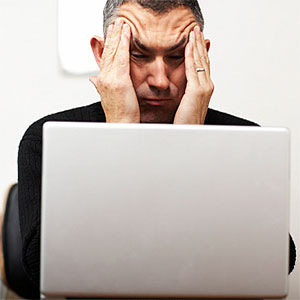 Man making faces from behind laptop © James Braund, Digital Vision, Getty Images