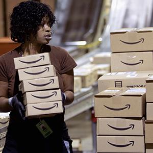 Credit: © Tim Shaffer/Reuters
Caption: A worker loads a shipment of boxes at an Amazon.com warehouse facility