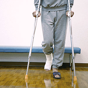 Man patient with cast on leg using crutches in exam room © DAJ, amana images, Getty Images